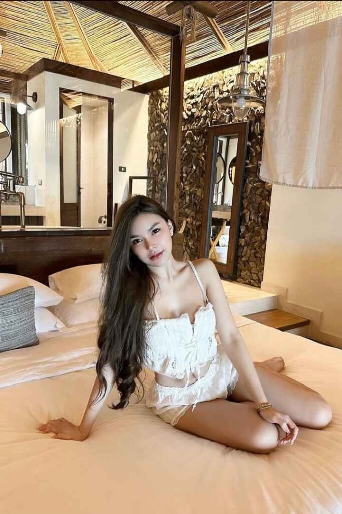 Woman in white lingerie relaxing on a bed in a luxurious hotel room.