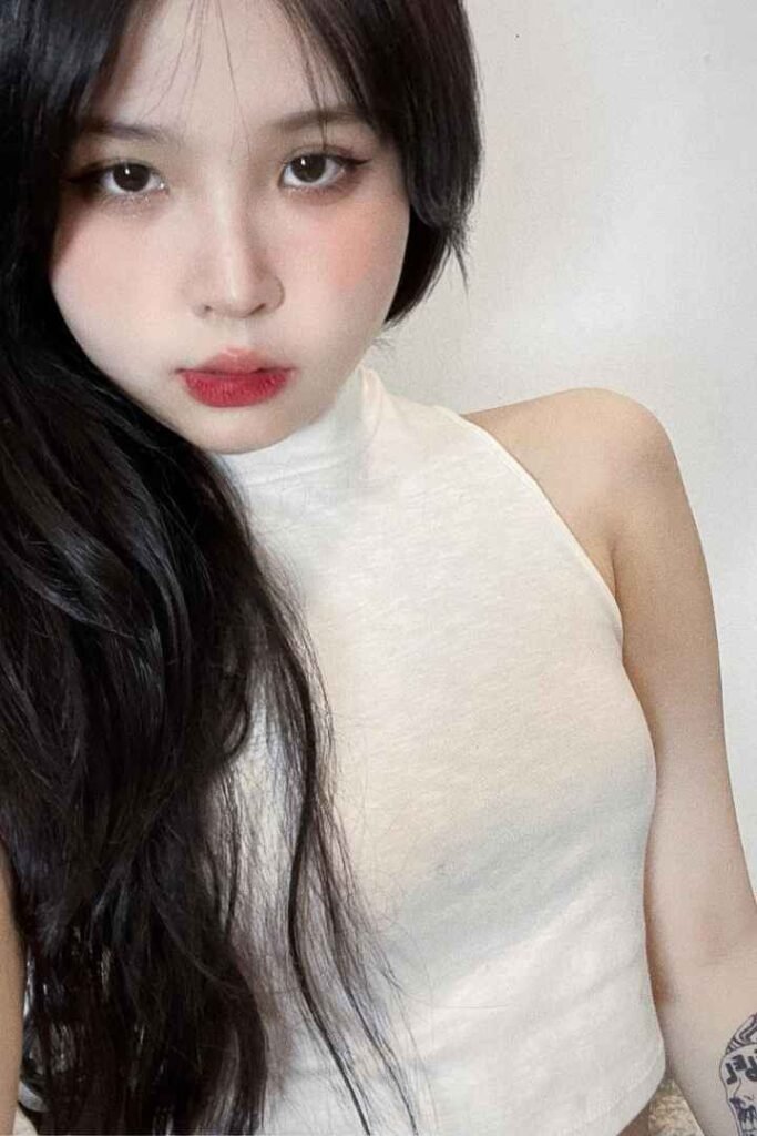 Portrait of a young woman with long black hair, wearing a white halter top.
